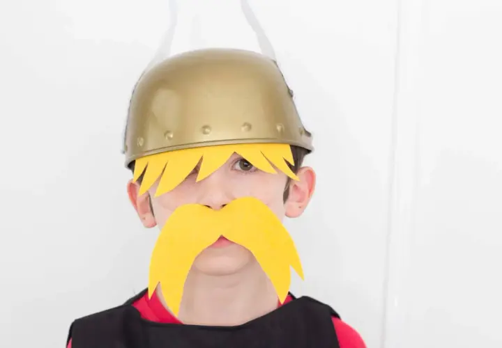 Niño con disfraz casero de Astérix y Obélix, luciendo casco dorado y bigote amarillo.