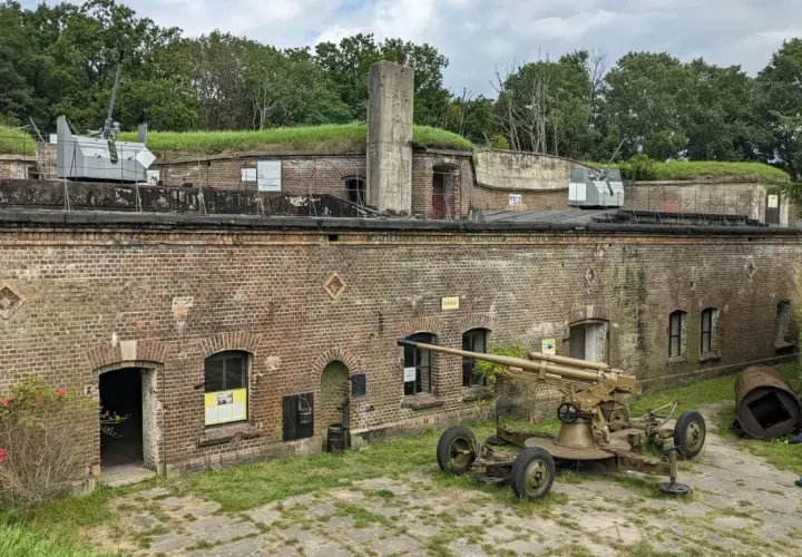 Fort Zachodni z działami na murach i ziemi. Dziecko biega obok zabytkowej broni.
