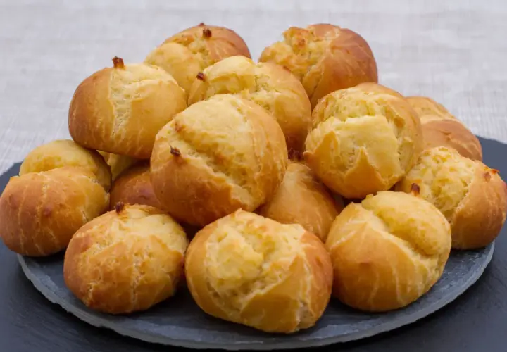 Pile de gougères dorées et gonflées, parfaites pour apprendre comment faire gonfler des gougères.