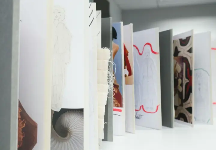 Un acheteur textile parcourt des croquis de mode, des échantillons de tissu et des motifs, imaginant de futures collections.
