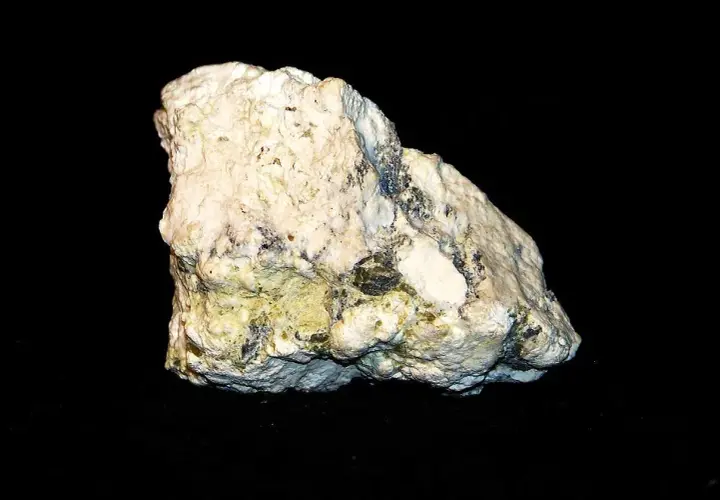 Biały, porowaty minerał z zielonkawo-żółtymi wtrąceniami, przypominający skałę, w której można znaleźć magnetyt.