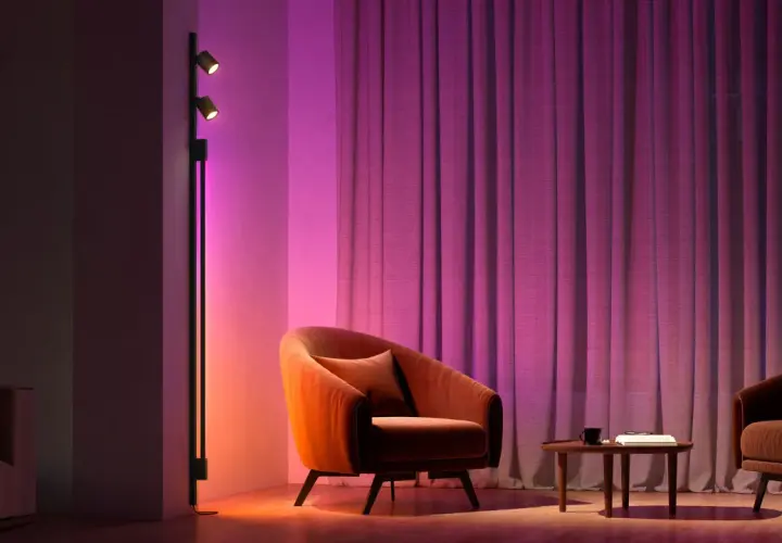 Sofá naranja y cortinas moradas iluminados por luces domoticas, creando un ambiente acogedor.