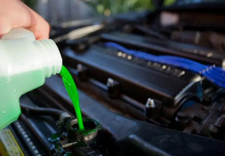 Vertiendo líquido refrigerante verde brillante en el radiador de un coche. El nivel líquido refrigerante es crucial para el motor.