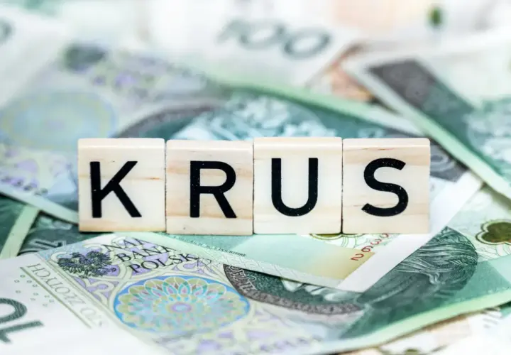 Litery KRUS na tle polskich banknotów. Zastanawiasz się, ile wynosi emerytura z KRUS?