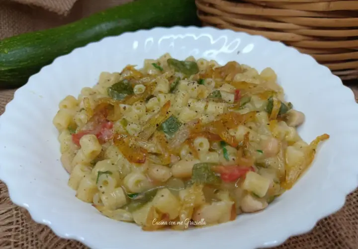 Un piatto invitante di pasta e zucchine alla pugliese, con fagioli e pomodoro, condito con erbe aromatiche.