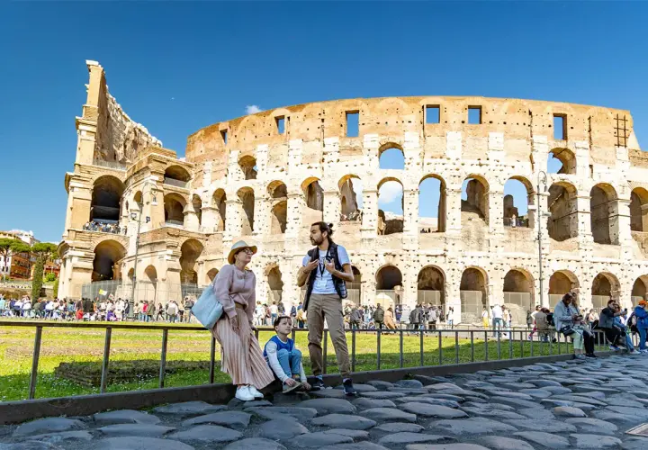 Famille admirant l'imposante arène de Rome, le Colisée, sous un ciel bleu éclatant.