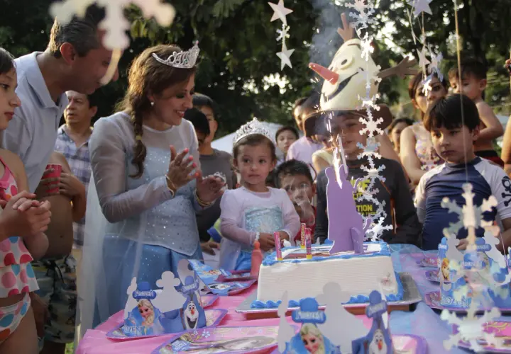 Celebración de cumpleaños en aula infantil con pastel de Frozen y niños emocionados.