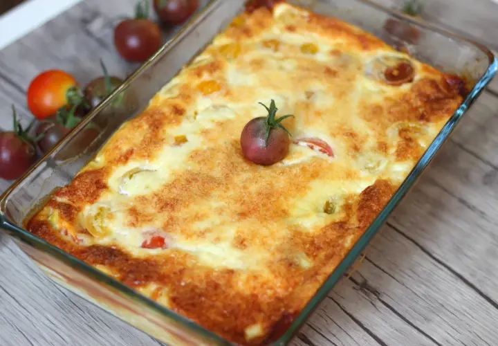 Un clafoutis tomates cerises doré et appétissant, garni d'une tomate cerise fraîche, prêt à être dégusté.