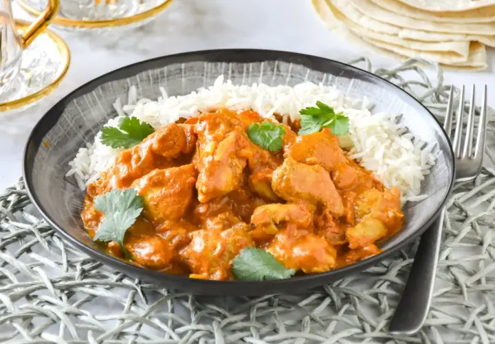 Un delicioso pollo tikka masala receta servido con arroz basmati y cilantro fresco.