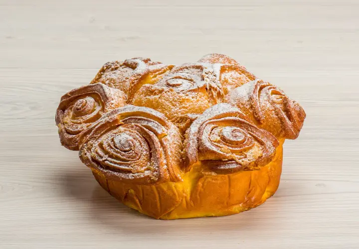 Una torta delle rose dorata e soffice, cosparsa di zucchero a velo, pronta per essere gustata.