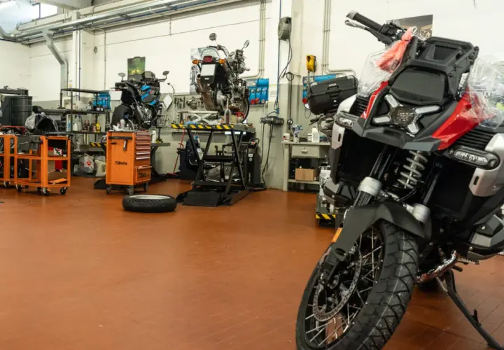 Officina moto con diverse moto in lavorazione. Un tecnico si chiede ogni quanto si fa il tagliando per mantenere al meglio il proprio mezzo.