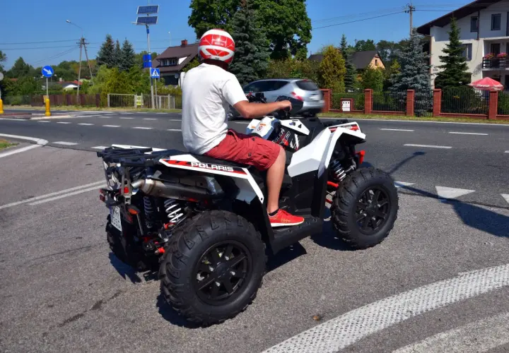 Mężczyzna w kasku na quadzie Polaris na drodze. Czy na quadzie trzeba mieć kask? Tak, dla bezpieczeństwa!