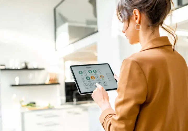 Mujer interactúa con una tablet que muestra la interfaz de un smart gateway para controlar su hogar inteligente.