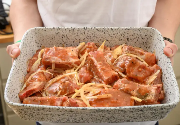 Surowe żeberka długo pieczone w marynacie z cebulą, gotowe do pieczenia.