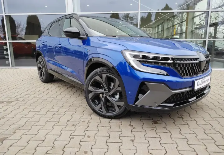 Niebieski Renault Austral prezentuje swoje imponujące wymiary na tle salonu samochodowego. Elegancki SUV z dynamiczną linią.