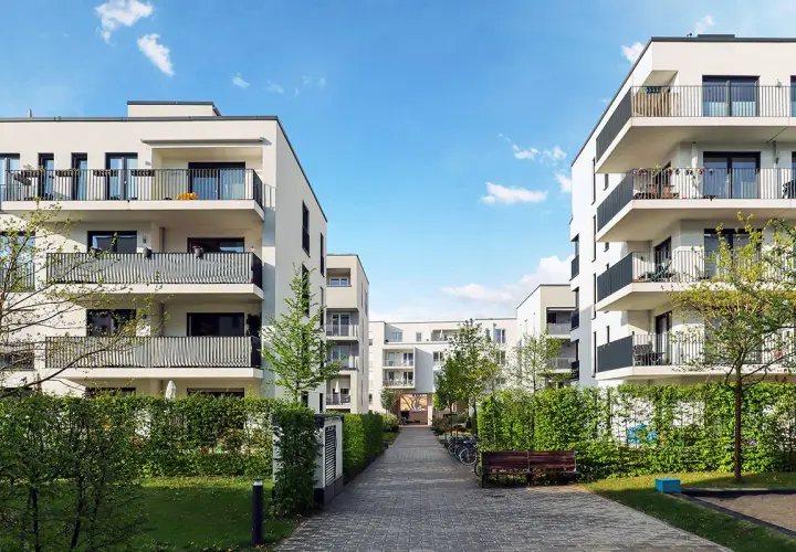 Immeubles modernes avec balcons, chemin pavé, verdure. Une location avec promesse de vente, un lieu de vie prometteur.