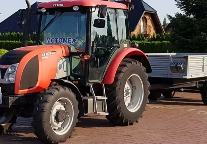 Czerwony Zetor z przyczepą, gotowy do pracy. Posiadanie prawa jazdy na traktor otwiera drogę do wielu możliwości.