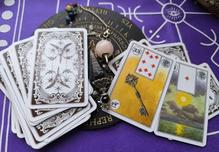 Odkryj znaczenie kart Lenormand. Na stole leżą karty, pendel i talizmany, gotowe do wróżenia.