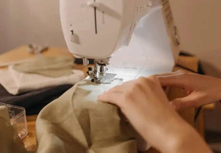 Hands guide fabric through a sewing machine, a peaceful scene of a sewing hobby.