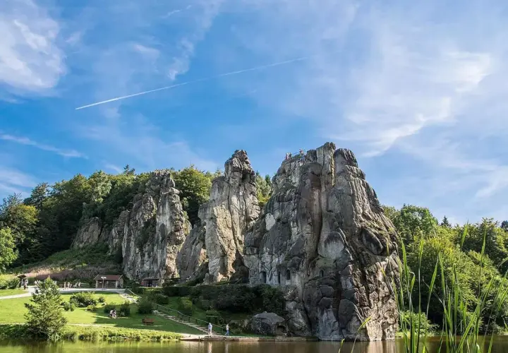 Felsformationen am Wasser, umgeben von grünen Bäumen, ein Ort, der an magische Orte in Deutschland erinnert.