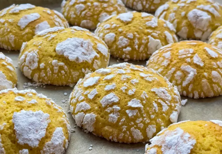 Popękane ciasteczka cytrynowe, posypane cukrem pudrem, wyglądają jak małe, słodkie śnieżki.