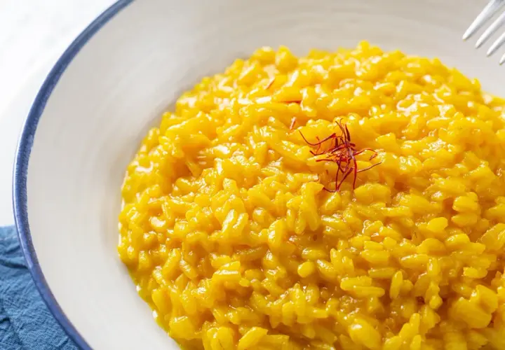 Risotto alla Milanese, un classico tra i piatti tipici lombardi, cremoso e profumato allo zafferano, guarnito con pistilli rossi.