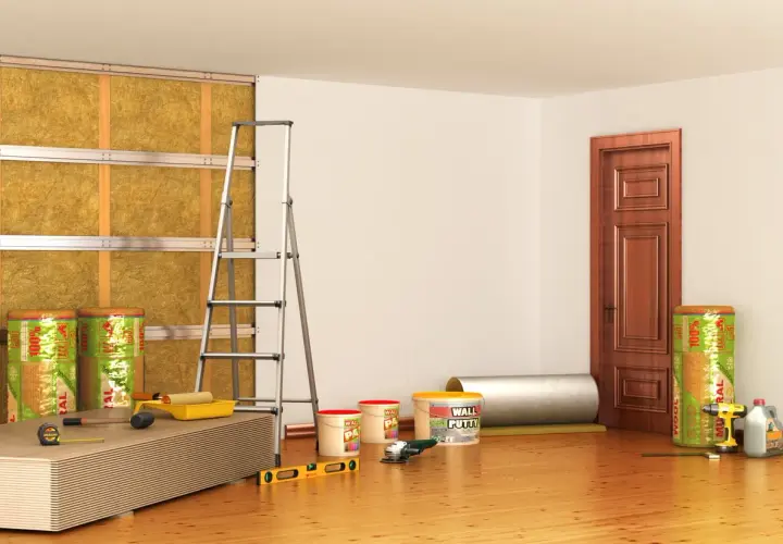 Materiali per isolamento termico e acustico, inclusi rotoli di lana minerale per un efficace cappotto interno antimuffa. Attrezzi da lavoro e pannelli pronti per l'installazione.