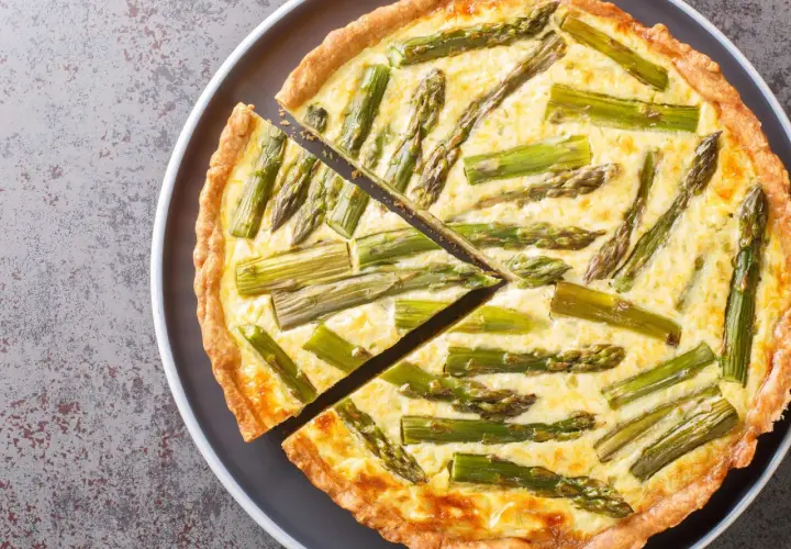 Eine köstliche Spargel Quiche mit einem goldbraunen Teigrand und saftiger Füllung, belegt mit frischem Spargel.