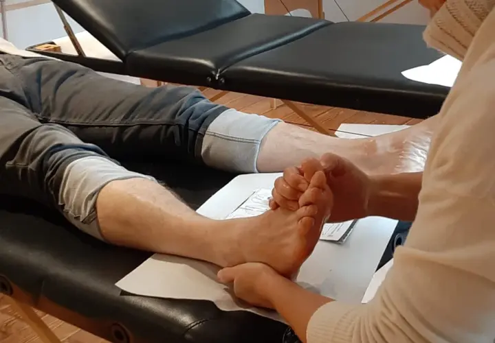 A person's foot is being massaged by another person's hands.