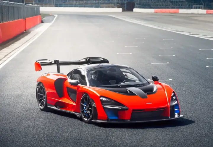Pomarańczowy McLaren Senna z czarnym spojlerem i detalami na torze wyścigowym.