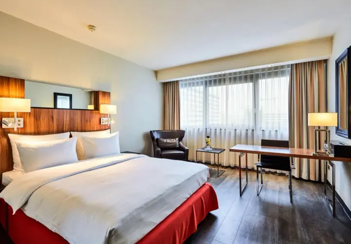Przytulny pokój w hotelu Radisson Blu Scandinavia Hotel Dusseldorf z wygodnym łóżkiem, fotelem i biurkiem.
