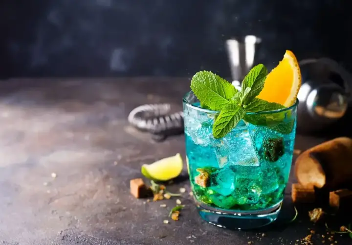 Orzeźwiający drink Blue Lagoon z miętą i pomarańczą, idealny na letnie wieczory.