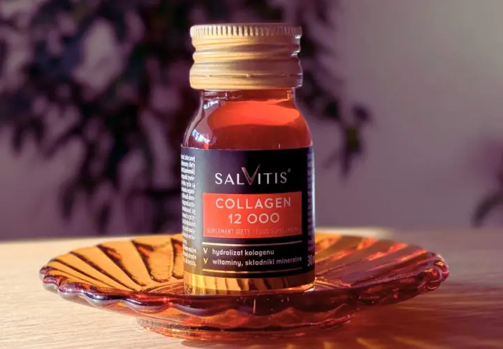 Szklana buteleczka suplementu diety SALVITIS Collagen 12 000, z płynem o bursztynowym kolorze, stoi na ozdobnej, pomarańczowej podstawce.