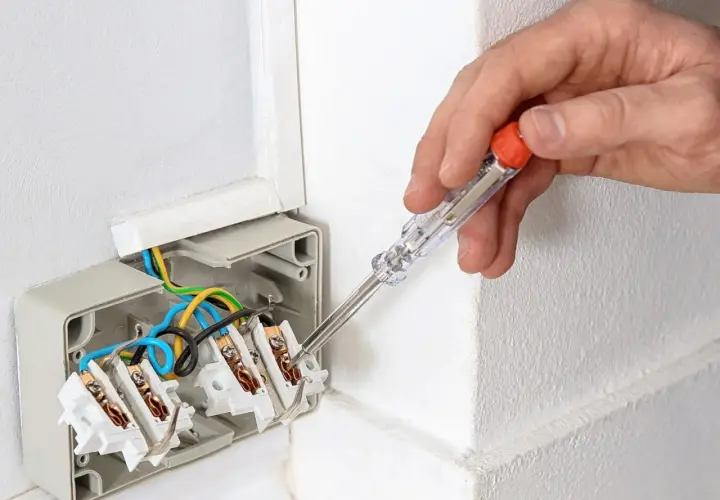 Ręka trzyma próbnik napięcia, sprawdzając instalację elektryczną. Tak działa próbnik napięcia, pomagając w bezpiecznym montażu.