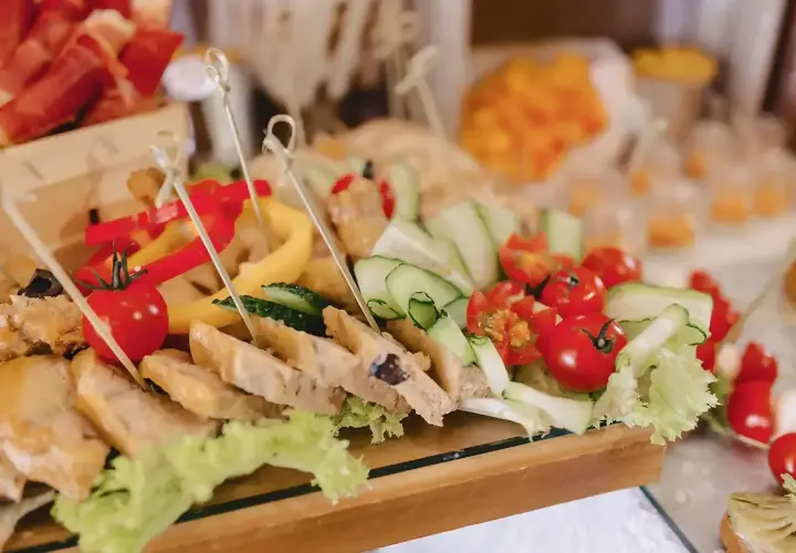 Un buffet froid festif pour un buffet départ retraite : brochettes de tomates cerises, concombres, poivrons et tranches de pain garnies.