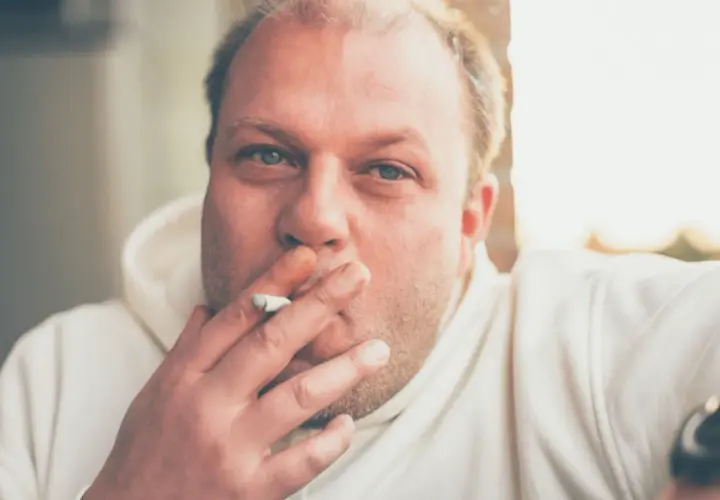 Hombre con cigarrillo en la mano, con el pelo rubio y ojos azules. Fumar hace que se te caiga el pelo.