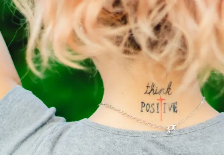 Mądre cytaty na tatuaż: "think POSITIVE" wytatuowane na karku, przypomina o pozytywnym nastawieniu.