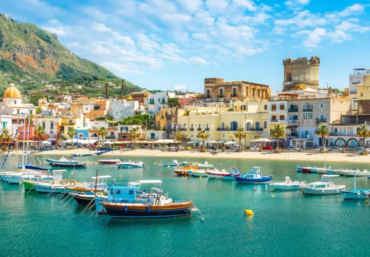 Un borgo marinaro con case colorate, una torre antica e barche nel mare cristallino. Un tuffo nella Ischia storia e bellezza.