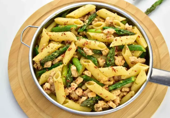 Penne z kurczakiem i szparagami, posypane papryką. Pyszne danie, które zachwyci każdego smakosza.