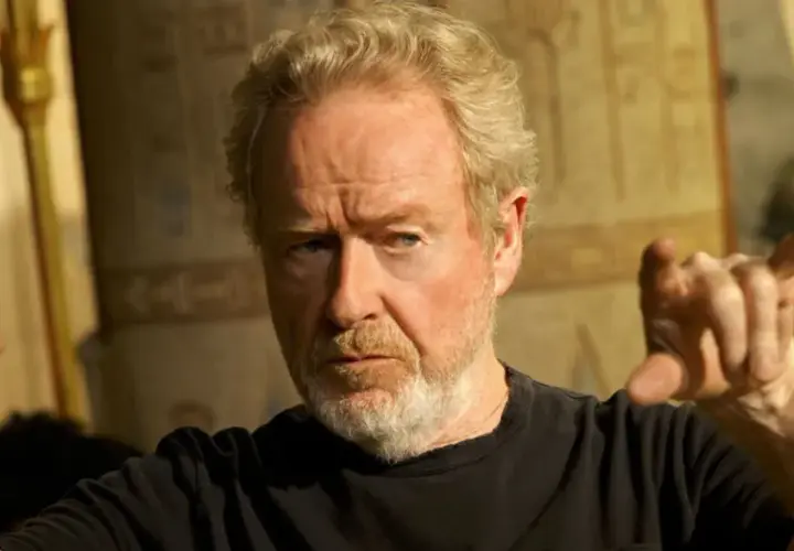 Reżyser Ridley Scott, znany z kultowych filmów, gestykuluje na tle starożytnych dekoracji.