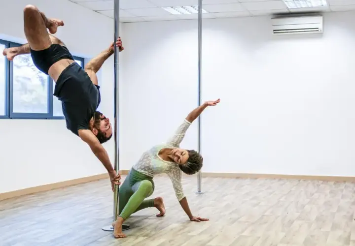 Mężczyzna w powietrzu, kobieta na podłodze. Ich taniec na słupie, niczym kołyska pole dance, tworzy hipnotyzującą choreografię.