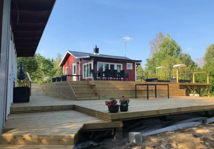 Stor altan runt husknut med trappor och sittplatser. Perfekt för sommarens grillkvällar.