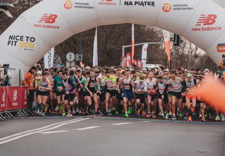 Start biegu na 10 km. Tłum biegaczy pod łukiem startowym New Balance, gotowi do rywalizacji.