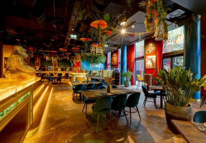 Egzotyczne wnętrze restauracji w Warszawie, z wielką złotą gorylicą przy barze i bujną roślinnością. Idealne miejsce na dobre jedzenie Warszawa.