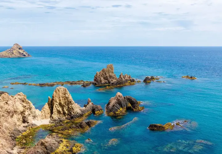 Formaciones rocosas emergen del mar turquesa en el arrecife de las sirenas Almería, un paisaje idílico.