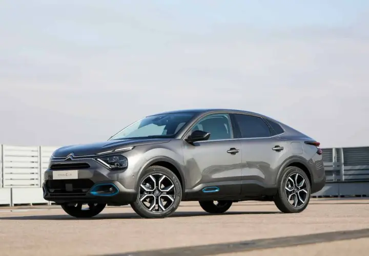 Szary Citroen C4X z niebieskimi akcentami stoi na betonowym placu.
