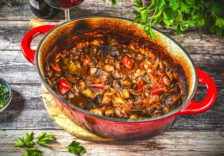 Herzhaftes Kalbsgulasch im roten Bräter, ein köstliches Rezept mit Paprika und Zwiebeln, bereit zum Servieren.