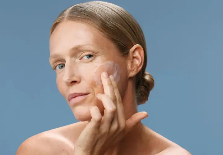 Donna applica crema viso. Scopri a cosa serve il peptide per una pelle radiosa e giovane.