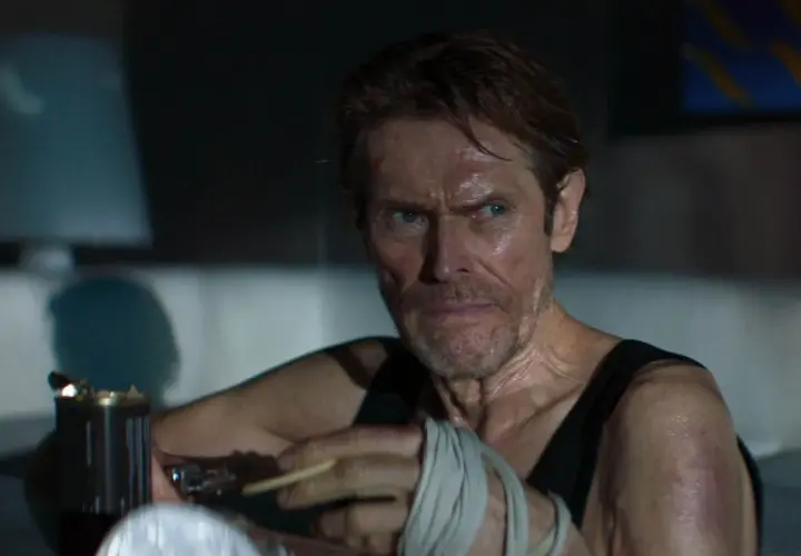 Willem Dafoe z papierosem w dłoni, z bandażami na ręce, w scenie sugerującej dobry thriller psychologiczny film.