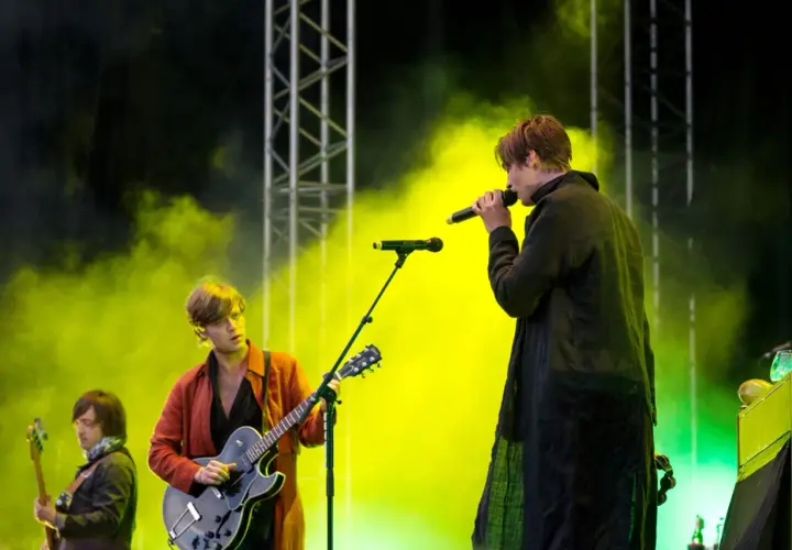 Mando Diao konsert med rök och ljus. Sångaren med mikrofon och gitarristen i röd jacka.